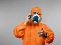 A smiling man wearing a gas mask and a hazmat suit